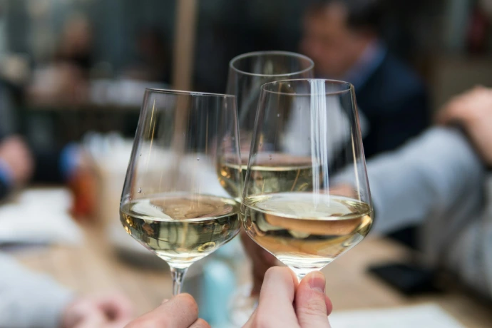 Trois verres de vin blanc qui trinquent lors d'un repas entre amis